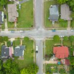 Aerial photo capturing an intersection in a suburban neighborhood with houses and greenery.