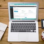 A cozy home office scene with a laptop, notebook, smartphone, and coffee, perfect for productivity.