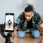 Man filming creative content with smartphone on gimbal indoors.